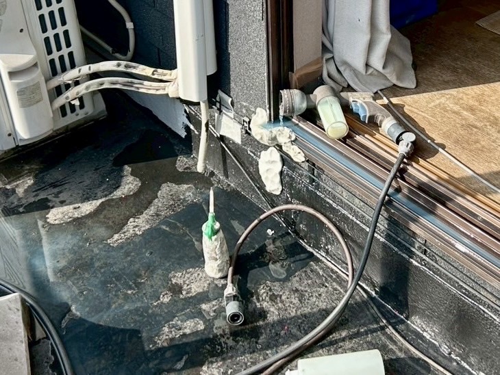 サッシ下部に緑色の調査液を注入し、パテで隙間を塞いで散水試験を行っている様子。