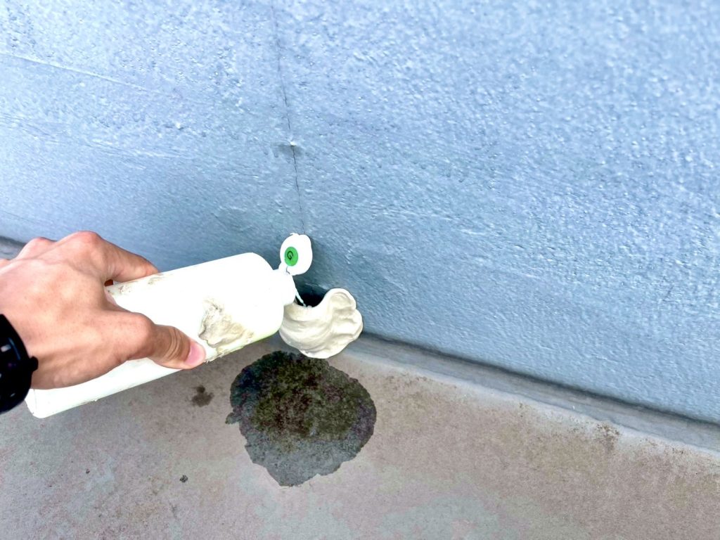 屋上防水面の亀裂に緑色調査液を注入して散水している様子